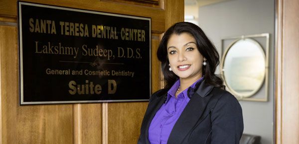 Dr. Lakshmy Sudeep standing in front of the door to Santa Teresa Dental Center where they offer a variety of dental services for the whole family.