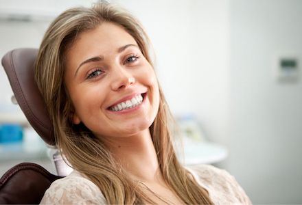 woman smiling in dentist's chair at Santa Teresa Dental Center after getting dental crowns